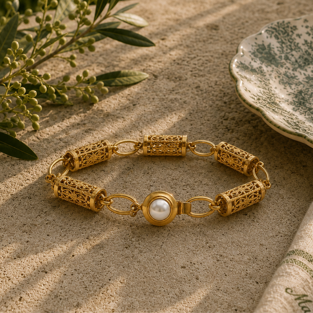 Gold bracelet with a pearl on a stone surface with greenery in the background