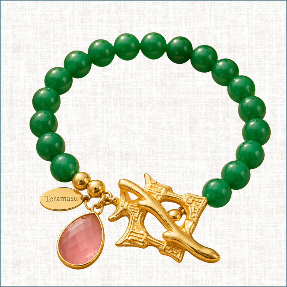Green beaded bracelet with gold charm and pink accent on a white background